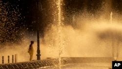 FILE - A municipal worker cools off next to a city fountain in Bucharest, Romania, July 11, 2024, as temperatures soared.