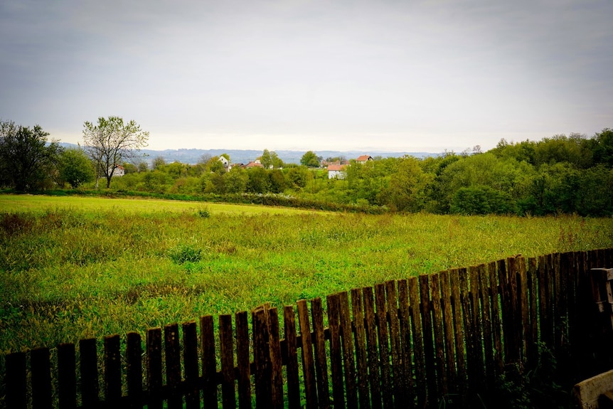 Small buildings visible in the distance, across rolling green hills.