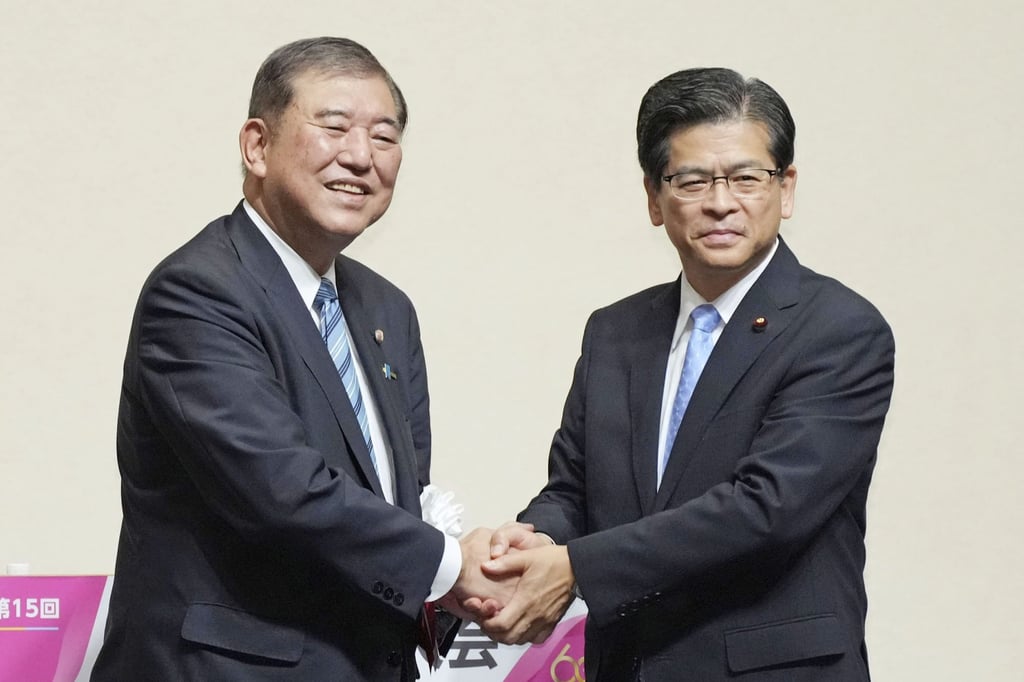 Shigeru Ishiba (left) and Keiichi Ishii, secretary of junior ruling coalition partner Komeito, shake hands at the Komeito party’s convention in Tokyo on September 28. Photo: Kyodo