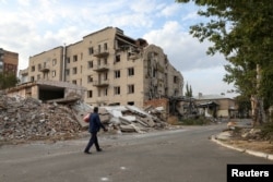 FILE - A man walks past a building damaged by a Russian military strike in the town of Pokrovsk in Donetsk region, Ukraine, Sept. 17, 2024.