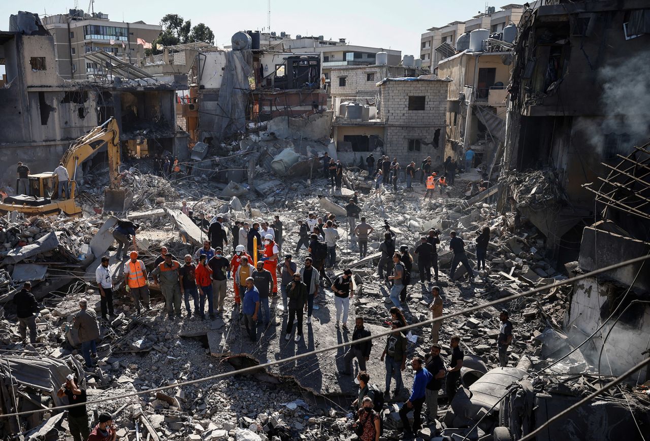 Emergency workers and locals stand at the site of a demolished building after an Israeli strike near the Rafik Hariri University Hospital in Beirut, Lebanon October 22, 2024.