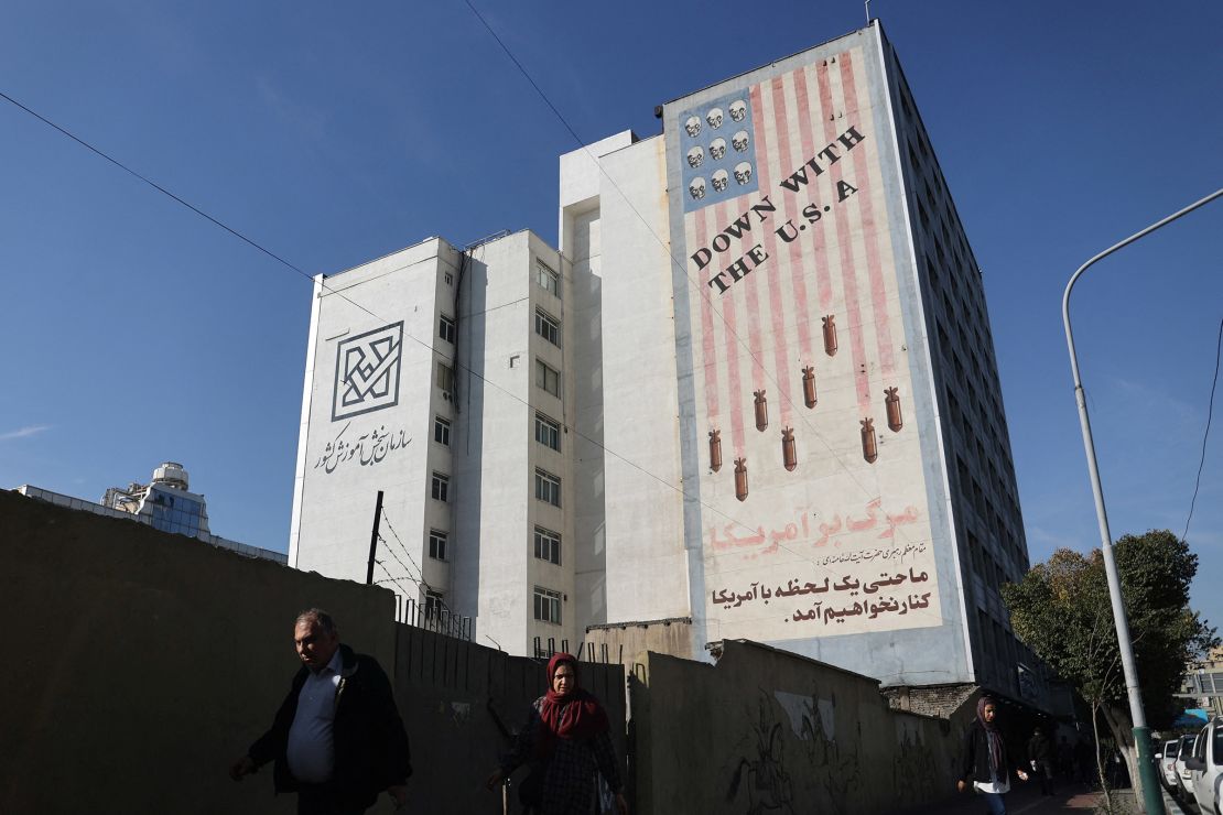 People walk near an anti-U.S. mural on a building after several explosions were heard, in Tehran, Iran, on October 26, 2024.