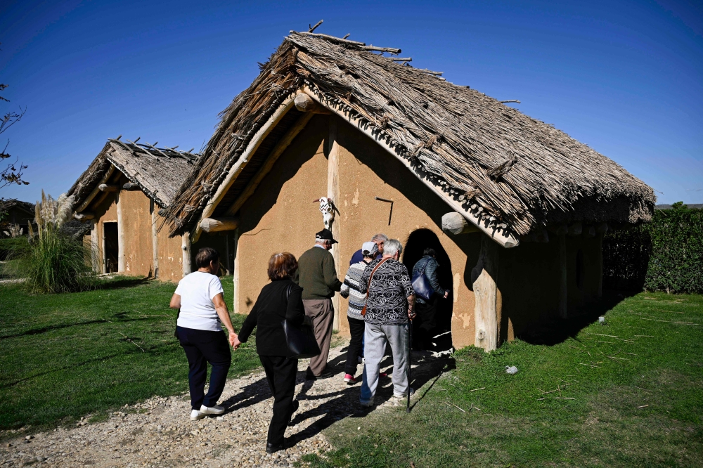 Tourists enter a replica of a prehistorical house as they visit the Historical Park of the village of Neofit Rilski, north-east Bulgaria October 10, 2024. — AFP pic