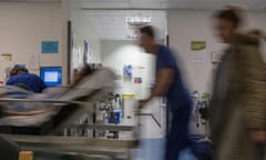 Blurred figures move through an NHS accident and emergency department