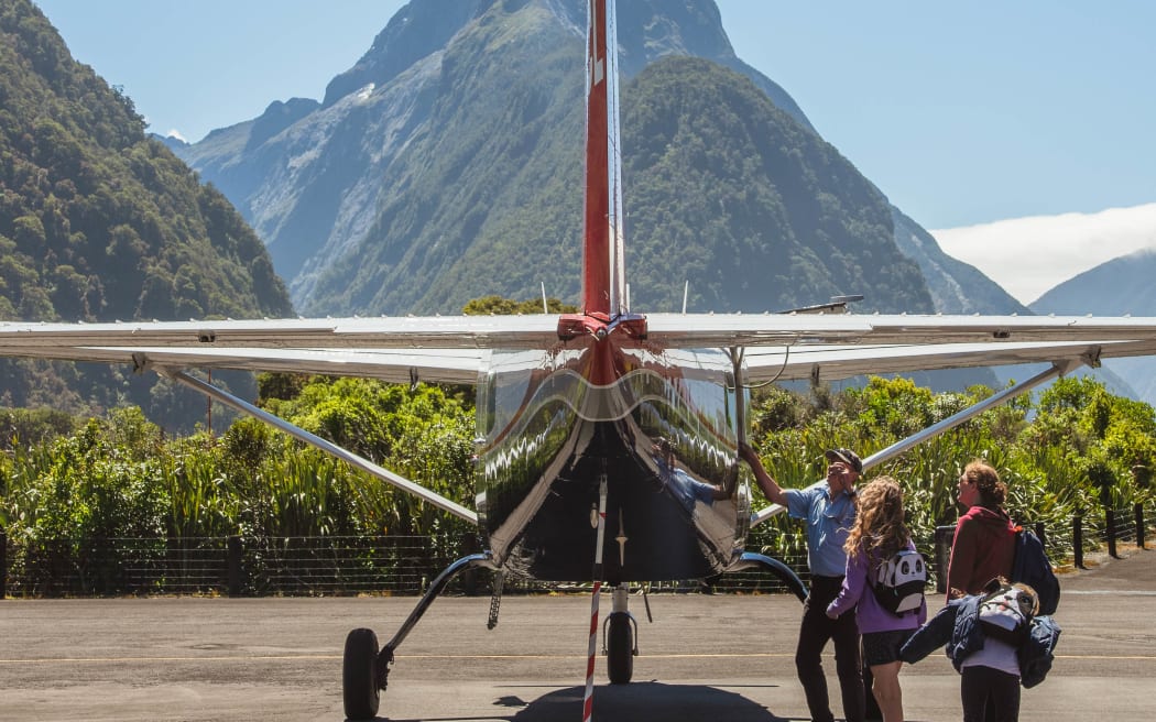 Small plane with Mitre Peak in background.