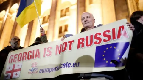 EPA Thousands protested against the contested result outside parliament on Monday in Tbilisi