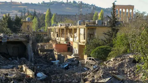 Getty Images The ancient Roman ruins of Heliopolis are seen in the background of an image showing damage and rubble from an Israeli strike in Lebanon