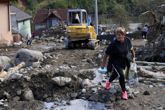 A local resident carries food for workers in a flooded residential area in Zlate, Bosnia and Herzegovina, October 7, 2024. 