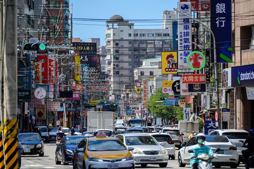 A busy street with signs on buildings and electric wires in between