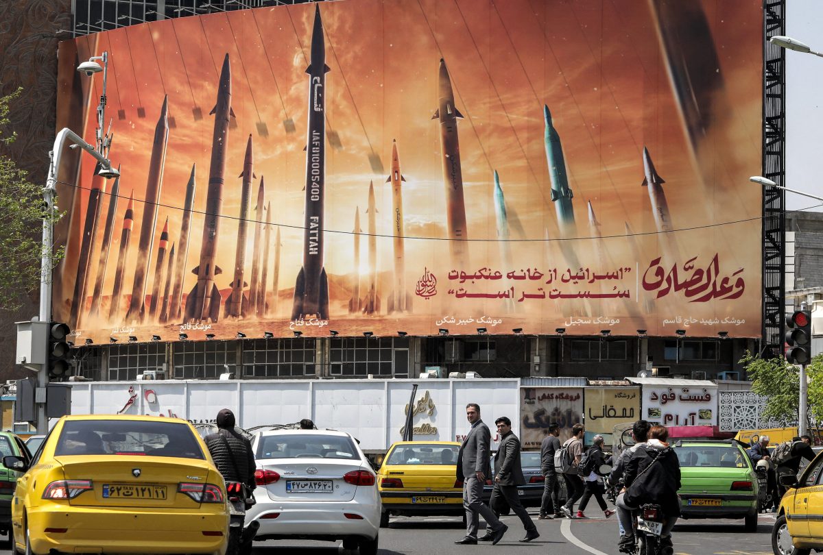 TOPSHOT - Motorists drive their vehicles past a billboard depicting named Iranian ballistic missiles in service, with text in Arabic reading "the honest [person's] promise" and in Persian "Israel is weaker than a spider's web", in Valiasr Square in central Tehran on April 15, 2024. Iran on April 14 urged Israel not to retaliate militarily to an unprecedented attack overnight, which Tehran presented as a justified response to a deadly strike on its consulate building in Damascus. (Photo by ATTA KENARE / AFP) (Photo by ATTA KENARE/AFP via Getty Images)