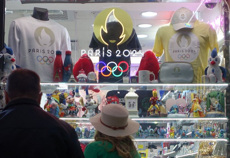 © Reuters. People watch objects at a shop at Champs-Elysees avenue with souvenir advertising the Paris 2024 Olympic and Paralympic Games in Paris, France, July 6, 2024.    REUTERS/Fabrizio Bensch/ File Photo