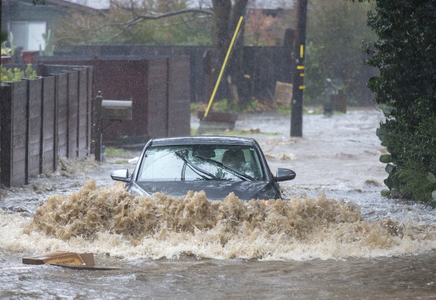 A car evacuates Paso Hondo Road as the Carmel River flood waters rise in Carmel Valley on Monday. (David Royal -- Herald file)