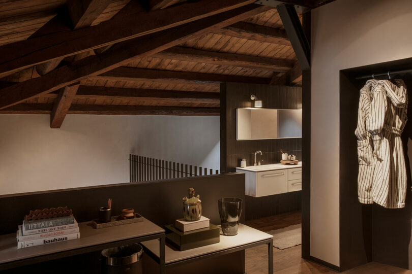 Partial view of a modern loft bedroom with a desk to the left and looking into the open bathroom space.