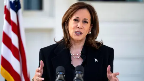 Reuters Kamala Harris stand in a black suit with her hands forward with the US Naval Observatory in Washington, U.S. in the background and an American flag 