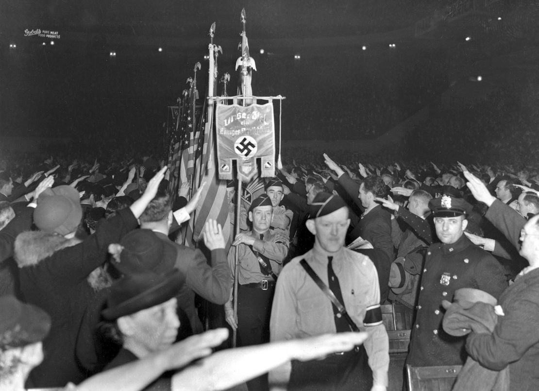 The crowd responds with a Hitler salute as uniformed members of a German American Bund color guard march at a gathering in Madison Square Garden on February 20, 1939.