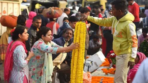 Getty Images People buy marigold flowers, fresh roses and garlands at the flower marker in Gurugram