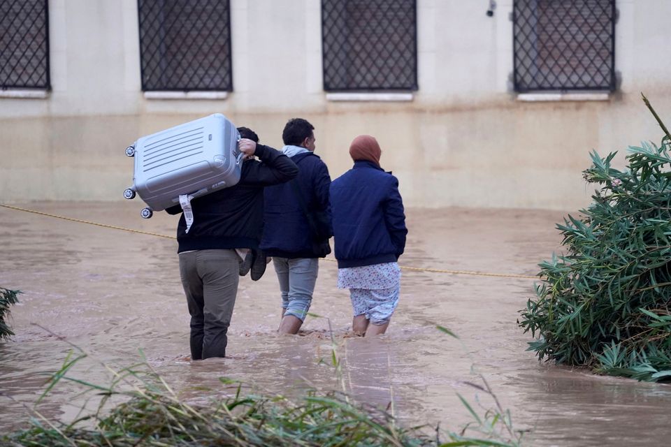 People, some with their belongings, walk through flooded streets in Valencia, Wednesday, Oct. 30, 2024. (AP Photo/Alberto Saiz)