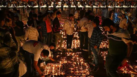 Getty Images People light earthen lamps on the banks of Sarayu river in Ayodhya on November 11, 2023