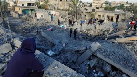 Reuters Palestinians inspect buildings destroyed in an Israeli strike in Khan Younis, in the southern Gaza Strip (25 October 2024)