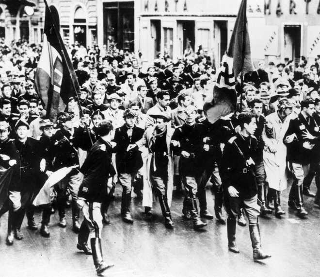 29th March 1941:  Italian students who have volunteered for military service, parade through the streets of Rome, carrying Italian and German flags.  (Photo by Keystone/Getty Images)