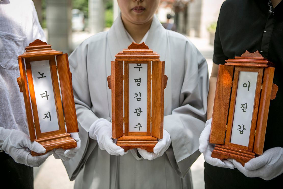 A Buddhist nun and staff of Good Nanum hold the name tablets of three deceased people before their cremation on June 16, 2016 in Goyang, South Korea.