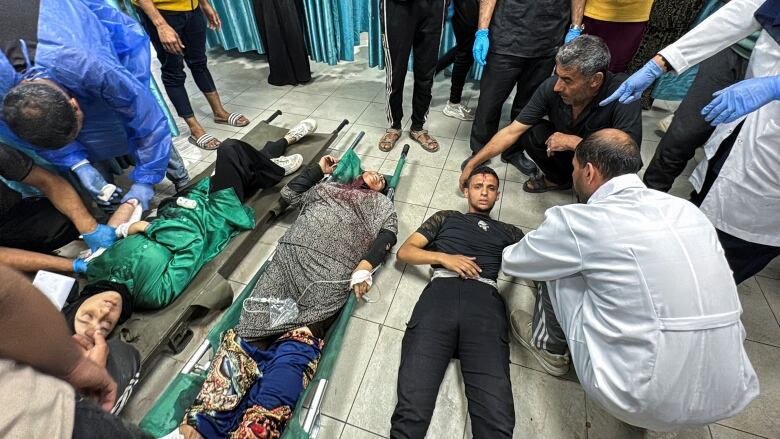 Three people wounded lay on the floor with a crowd surround them at a hospital.