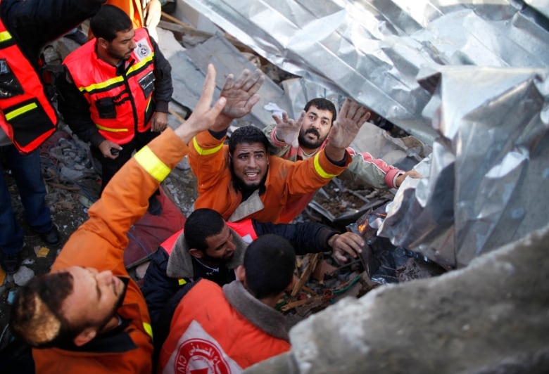 A group of men try to pull people out of rubble